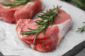Fresh raw meat with rosemary on parchment paper, closeup