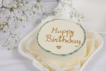 Fototapeta na wymiar Delicious decorated Birthday cake near dry flowers on white cloth