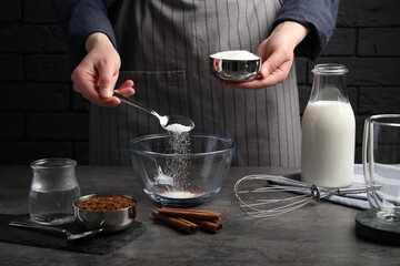 Making dalgona coffee. Woman pouring sugar into bowl at grey table, closeup