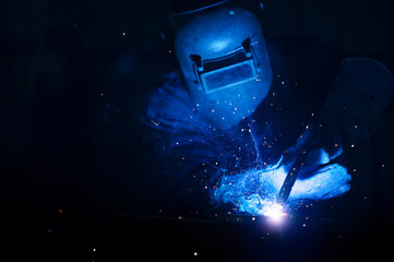 Asian worker wearing industrial uniform and welding mask at welding factory Safety concepts in the...