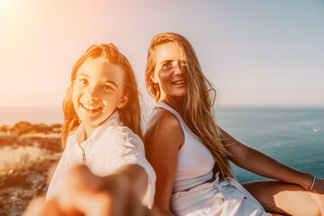 Naklejka premium Sea family vacation together, happy mom and teenage daughter hugging and smiling together over sunset sea view. Beautiful woman with long hair relaxing with her child. Concept of happy friendly family