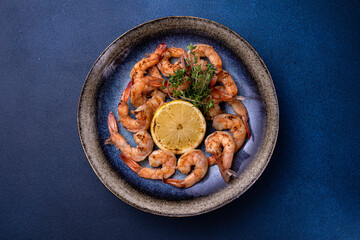 A bowl of shrimp with lemon on the side