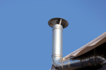 Metal chimney pipe on the roof of house