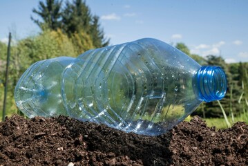 pusta butelka plastikowa leżąca na ziemi bez śmietnika. - obrazy, fototapety, plakaty