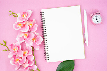 The Blank open notebook and clock with pink color orchid for your text or message.
