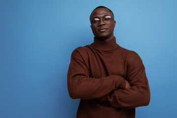 Obraz premium elegant young african brunet male businessman in stylish brown sweater and glasses on studio background with copy space