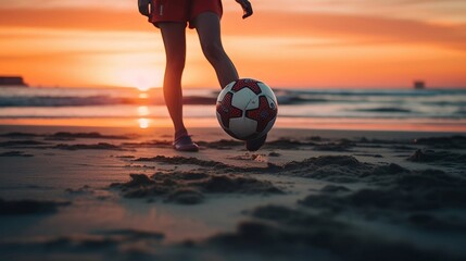 A person kicking a soccer ball on the beach during sunset, low angle shot.