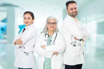 Team of indian doctors standing standing cross arms at hospital, healthcare and medical concept.