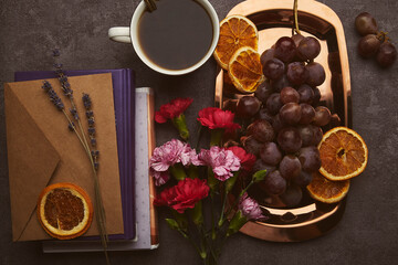 Obraz na płótnie Canvas Aesthetic feminine flat lay snacks with grapes, cup of coffee, books and flowers on the golden tray