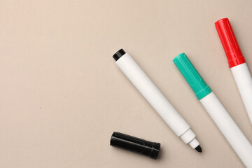 Bright color markers on beige background, flat lay. Space for text