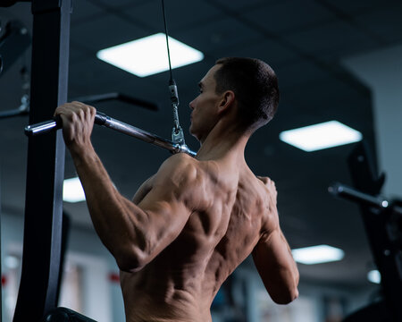 A man does a chest pulldown in the gym.
