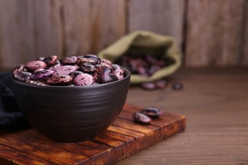 Bowl with dry kidney beans on wooden table, closeup. Space for text