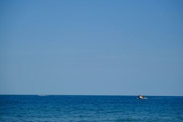 Fototapeta na wymiar Seascape with Boat and Skyline on Deep Blue Sea