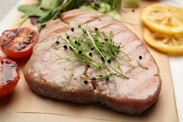 Delicious tuna steak with microgreens on parchment paper, closeup