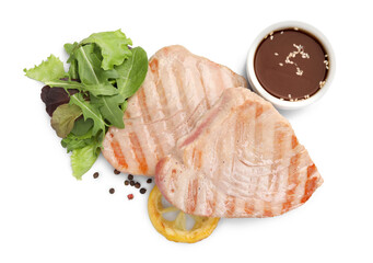 Delicious tuna steaks with salad, sauce and lemon isolated on white, top view