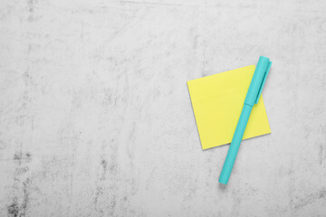 Paper note and color marker on light grey background, top view. Space for text