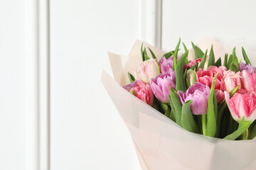 Bouquet of beautiful tulips near white wall, closeup. Space for text