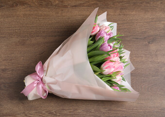 Bouquet of beautiful tulips on wooden table, top view
