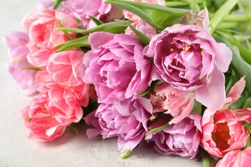 Beautiful bouquet of colorful tulip flowers on light table, closeup