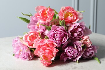 Beautiful bouquet of colorful tulip flowers on light table, closeup
