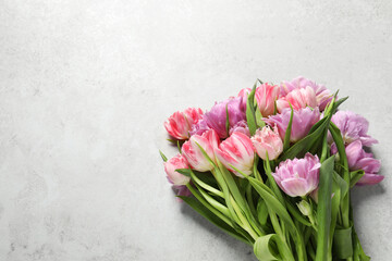 Beautiful bouquet of colorful tulip flowers on light grey table, top view. Space for text