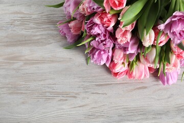 Beautiful bouquet of colorful tulip flowers on wooden table, top view. Space for text