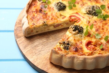 Delicious homemade vegetable quiche on light blue table, closeup