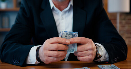 Unknown successful bearded businessman counting his profit after concluding business deal and hides the part of proceeds in his pocket