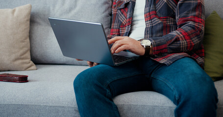 Portrait of likable thoughtful concentrated bearded man in glasses which working on laptop at home...