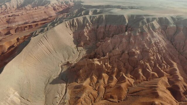 Aerial view of spectacular red rock formations, arid area - Azhirzhar Tract, Kazakhstan. Rocky cliffs of sandstone red, yellow, white (Drone 4K)