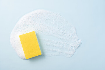 Cleaning sponge and a soapy foam on a blue background. Cleaning concept, cleaning service. Banner. Flat lay, top view