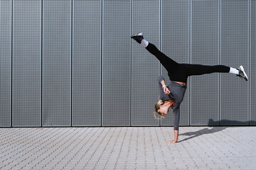 Woman athlete wearing female sportswear doing cartwheel movement on the street