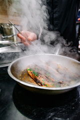 man chef cooking fried meat slice in frying pan on restaurant kitchen