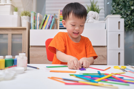 Cute happy smiling little Asian 3 years old toddler boy enjoy using glue doing arts at home, Fun paper and glue crafts for toddlers, Children's Art Project, DIY Toys for kids concept