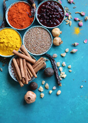 Spices and herbs on turquoise background with copy space. Food and cuisine ingredients. Colorful spices in bowls on blue background, top view