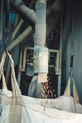 dried beans being deposited in a sack by a machine in a factory