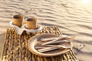 kraft paper cups and disposable paper plates and forks at the beach. eco friendly