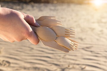 wooden spoons in hand on sand background