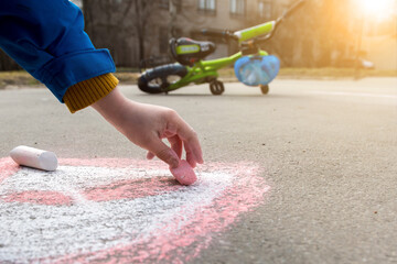 a child draws with chalk on the asphalt on the background of a bicycle