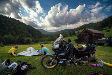 Setting up a blue tent with a great view of the mountains. A trip on a motorbike. A touring motorcycle with lots of gear. Bags, luggage. A couple of bikers, stopped for the night in a camp. Ukraine