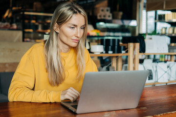 Caucasian woman working on a laptop in a cafe