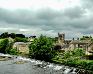 The weir created close to the old River Aire ford to supply energy to the corn mill is now a tourist attraction with the town of Bingley and its Parish Church in the background