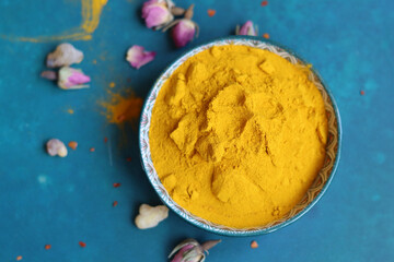 Turmeric powder in a bowl on a blue background, top view