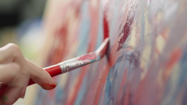Close-up red kiss paints on canvas. The young artistic soul creates amazing drawings on an easel, reproducing his thoughts and experiences on canvas.