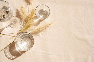 Glasses with water and contrasting shadows. Fashion trend. Sunny day. Empty space. Mockup