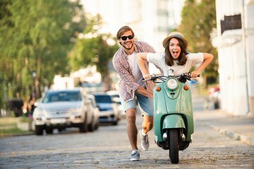 Laughing couple riding on a scooter in town