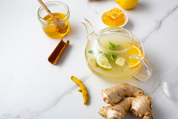 Close up of orange ginger tea in glass teapot  food roots turmeric fruits honey cinnamon stick