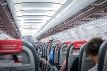 Interior de un avión comercial con vista a los asientos con pasajeros.