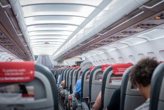 Interior de un avi&oacute;n comercial con vista a los asientos con pasajeros.