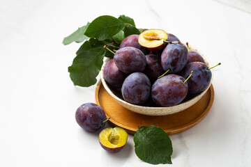 Fresh purple fruit plum on wooden bowl light background autumn food - Powered by Adobe
